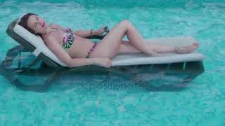 Beautiful tanned sporty slim woman relaxing in swimming pool spa.